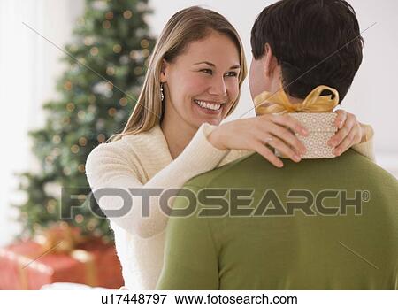 Woman holding gift and hugging husband View Large Photo Image Stock Photo - Woman holding gift and hugging husband. Fotosearch