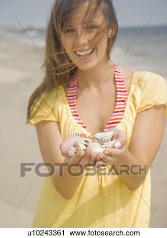 Stock Image - Woman holding handful of shells. Fotosearch
