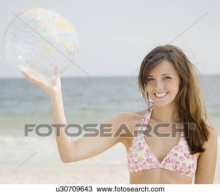 Stock Image - Woman holding inflatable globe. Fotosearch