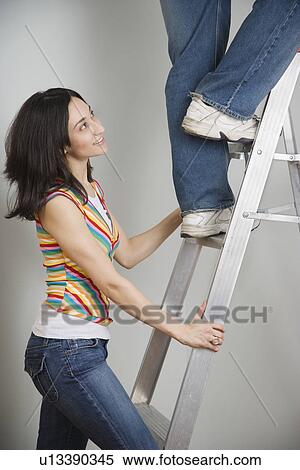 Woman holding ladder while man climbs View Large Photo Image Stock Photography - Woman holding ladder while man climbs. Fotosearch