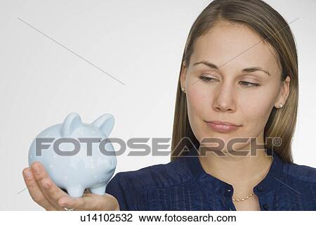 Stock Image - Woman holding piggy bank. Fotosearch