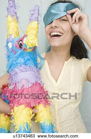 Woman holding pinata and peeking under blindfold View Large Photo Image Stock Image - Woman holding pinata and peeking under blindfold. Fotosearch