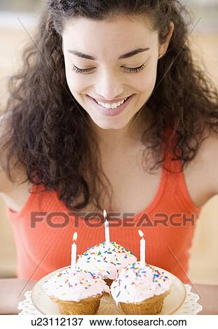 Stock Photo - Woman holding plate of cupcakes with candles. Fotosearch