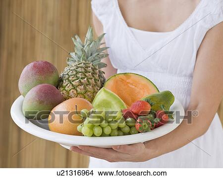Picture - Woman holding plate of fruit. Fotosearch