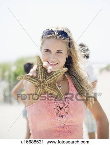 Stock Image - Woman holding up starfish. Fotosearch