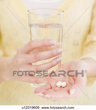 Stock Photo - Woman holding water and medication. Fotosearch