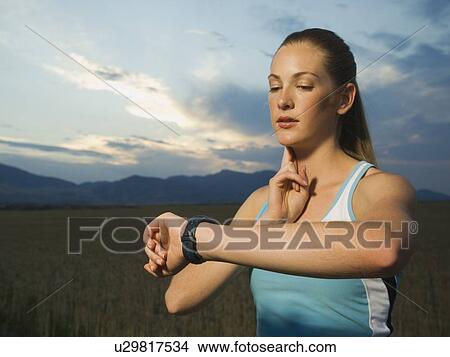 Woman in athletic gear checking pulse View Large Photo Image Picture - Woman in athletic gear checking pulse. Fotosearch
