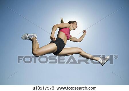 Stock Image - Woman in athletic gear jumping. Fotosearch
