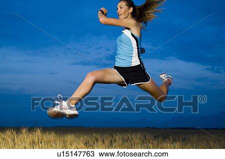 Stock Image - Woman in athletic gear jumping. Fotosearch