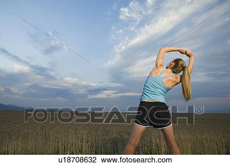 Stock Image - Woman in athletic gear stretching. Fotosearch