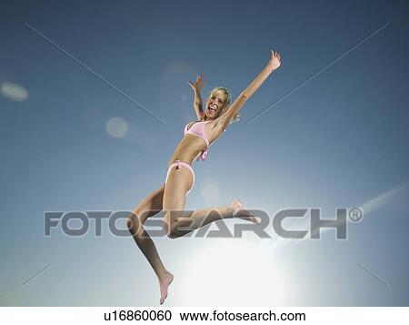 Stock Image - Woman in bathing suit jumping. Fotosearch