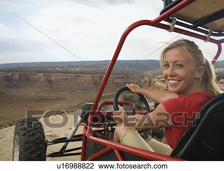 Stock Image - Woman in off-road vehicle at edge of cliff. Fotosearch