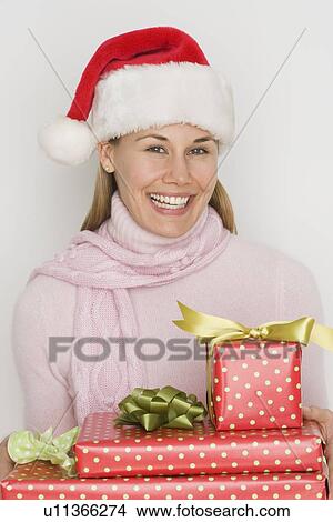 Picture - Woman in Santa Claus hat holding gifts. Fotosearch