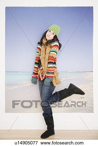 Stock Photo - Woman in winter clothing in front of beach picture. Fotosearch