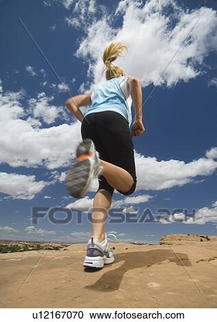 Stock Image - Woman jogging in desert. Fotosearch