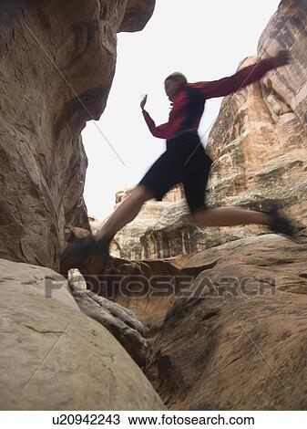 Woman jumping over rock formations View Large Photo Image Stock Image - Woman jumping over rock formations. Fotosearch