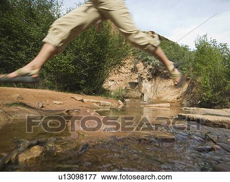 Woman jumping over stream View Large Photo Image Stock Photo - Woman jumping over stream. Fotosearch