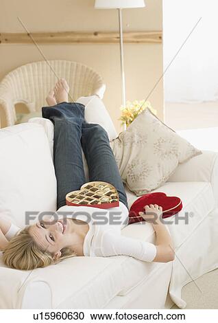 Woman laying on sofa with box of candy View Large Photo Image Stock Image - Woman laying on sofa with box of candy. Fotosearch