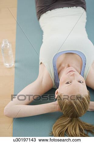 Stock Image - Woman laying on yoga mat. Fotosearch
