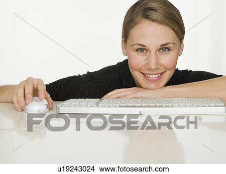 Picture - Woman leaning on table next to keyboard. Fotosearch