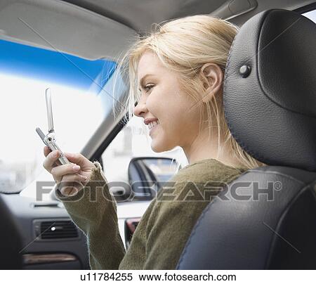Woman looking at cell phone in car View Large Photo Image Stock Photography - Woman looking at cell phone in car. Fotosearch