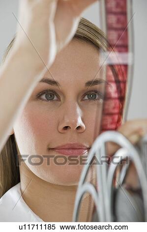 Stock Photography - Woman looking at movie film. Fotosearch