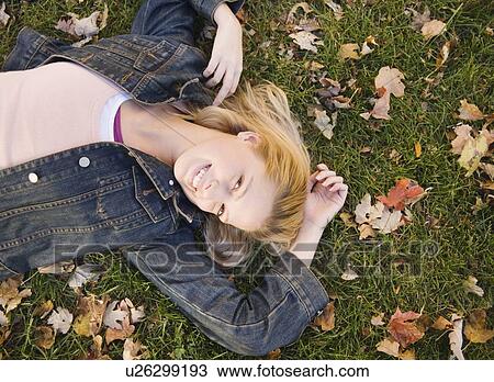 Woman lying in grass on a fall day View Large Photo Image Stock Image - Woman lying in grass on a fall day. Fotosearch