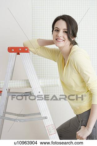 Woman on ladder with roll of wallpaper View Large Photo Image Picture - Woman on ladder with roll of wallpaper. Fotosearch