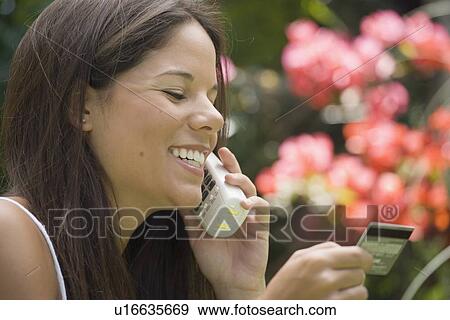 Stock Photo - Woman on phone holding credit card. Fotosearch