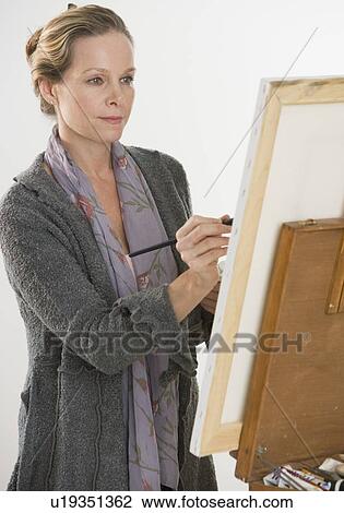 Stock Image - Woman painting at easel. Fotosearch