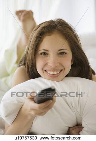 Stock Image - Woman pointing remote control. Fotosearch