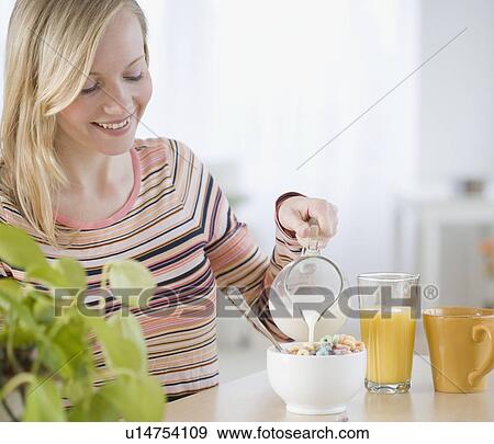 Stock Photo - Woman pouring milk into cereal. Fotosearch