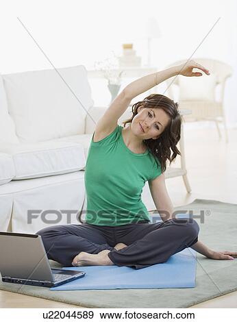 Stock Photo - Woman practicing yoga next to laptop. Fotosearch