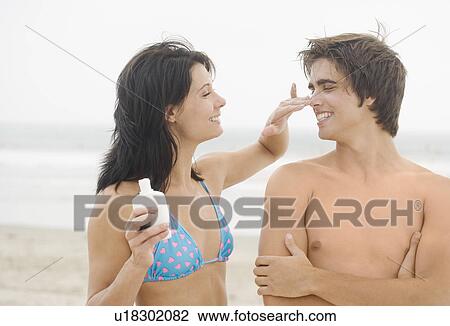 Woman putting sunscreen on man's nose at beach View Large Photo Image Stock Image - Woman putting sunscreen on man's nose at beach. Fotosearch