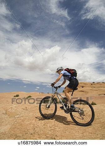 Picture - Woman riding mountain bike in desert. Fotosearch