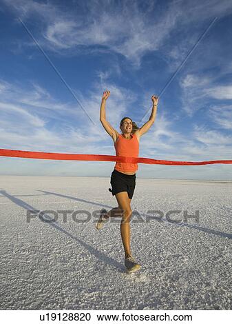 Stock Image - Woman running across finish line, Utah, United States. Fotosearch