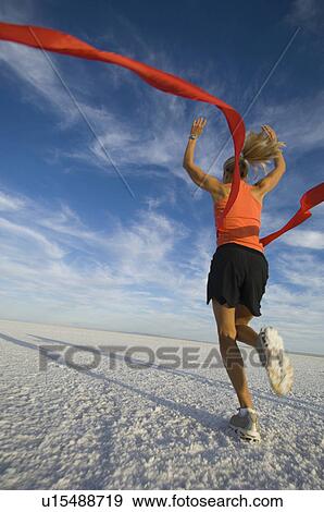 Stock Photo - Woman running across finish line, Utah, United States. Fotosearch