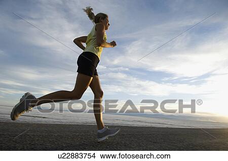 Picture - Woman running on road, Utah, United States. Fotosearch