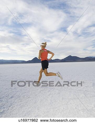 Stock Image - Woman running on salt flats, Utah, United States. Fotosearch