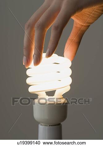 Woman screwing in energy-efficient light bulb View Large Photo Image Stock Image - Woman screwing in energy-efficient light bulb. Fotosearch