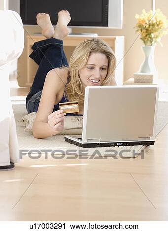 Stock Image - Woman shopping online on floor. Fotosearch