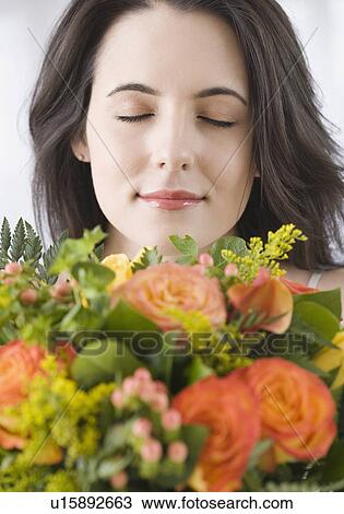 Stock Image - Woman smelling bouquet of flowers. Fotosearch