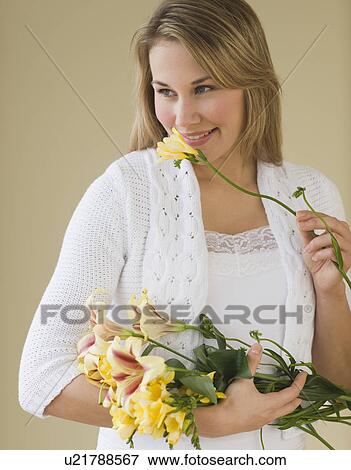 Stock Photo - Woman smelling cut flower. Fotosearch