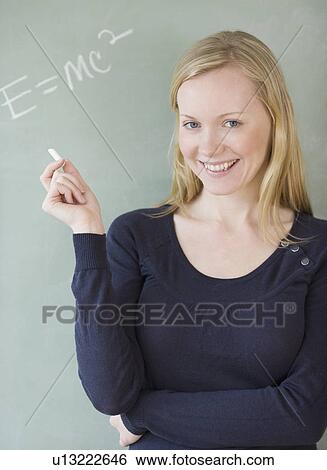 Woman standing in front of blackboard View Large Photo Image Stock Photograph - Woman standing in front of blackboard. Fotosearch