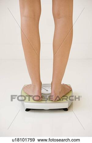 Stock Photo - Woman standing on scale. Fotosearch
