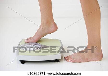 Woman stepping on scale View Large Photo Image Stock Image - Woman stepping on scale. Fotosearch