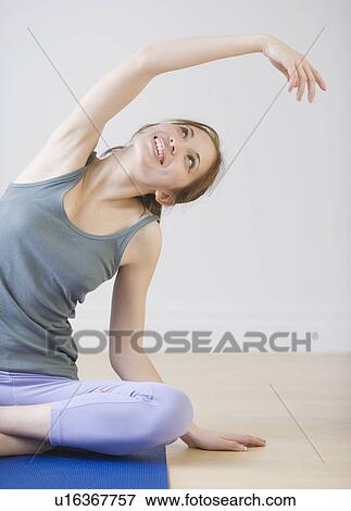 Stock Photo - Woman stretching on yoga mat. Fotosearch