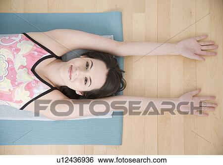 Woman stretching on yoga mat View Large Photo Image Stock Photograph - Woman stretching on yoga mat. Fotosearch