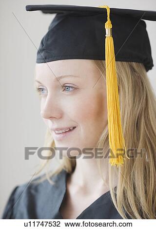 Stock Image - Woman wearing graduation cap and gown. Fotosearch
