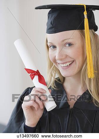 Stock Image - Woman wearing graduation cap and gown. Fotosearch